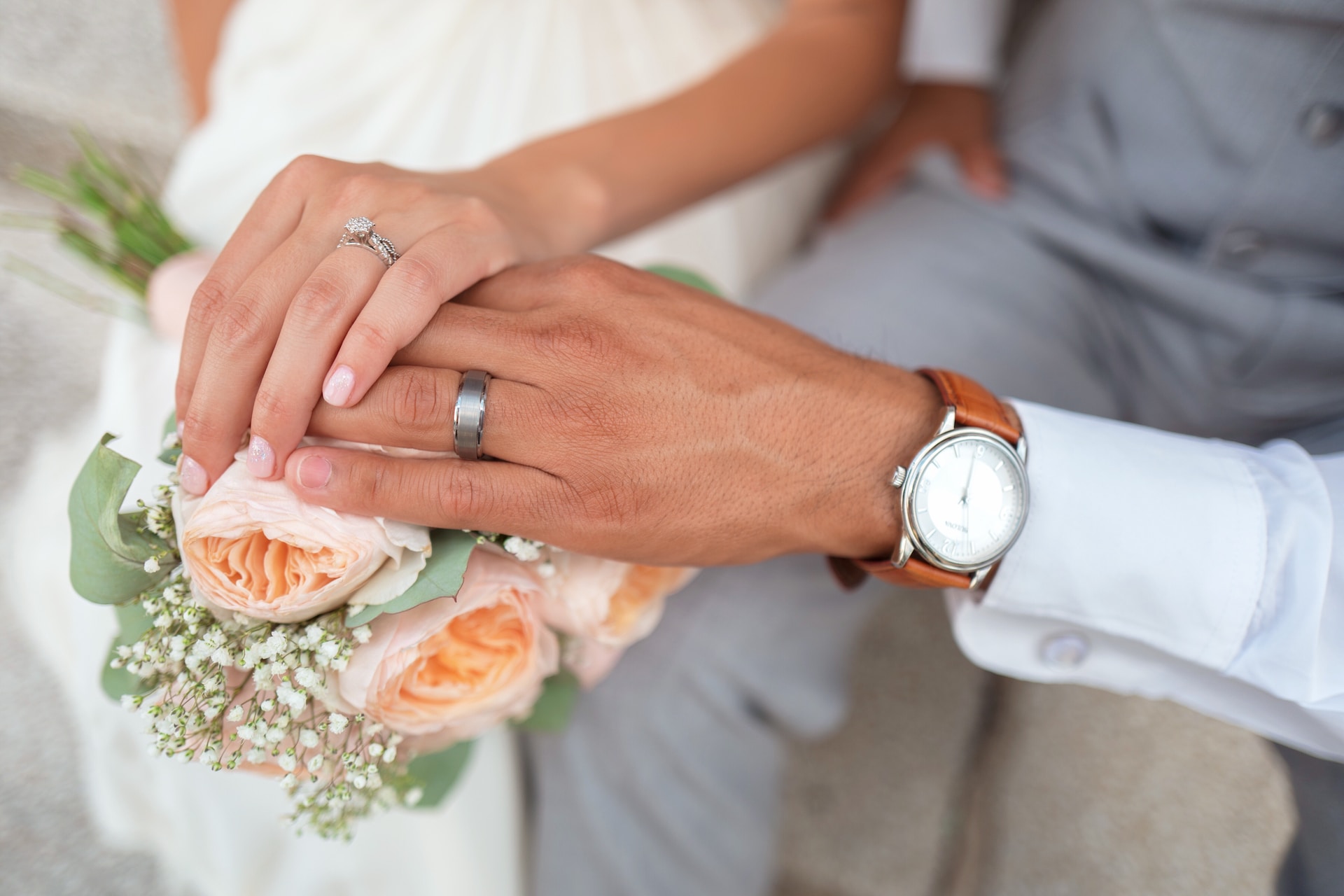A tender moment as the bride and groom's hands gently clasp together.
