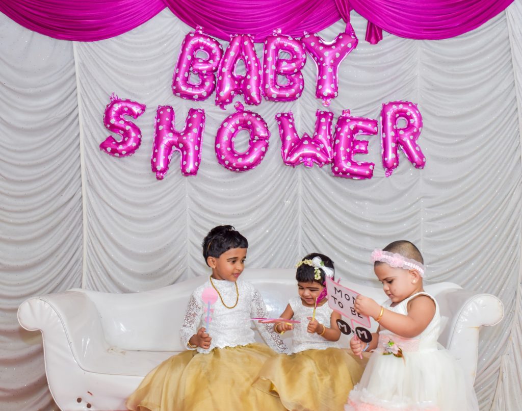 Three children playing joyfully at a baby shower celebration.
